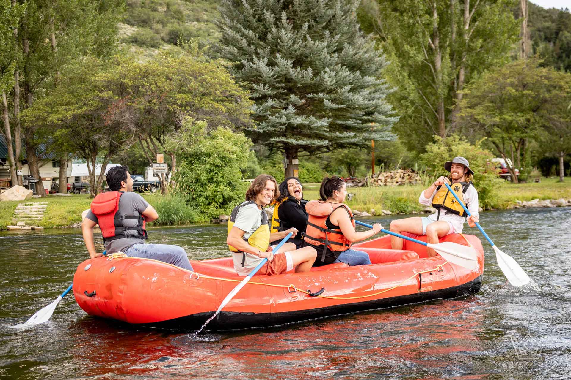 Three friends and their two river guides rafting on the smooth waters of the Provo River near Deer Creek Dam